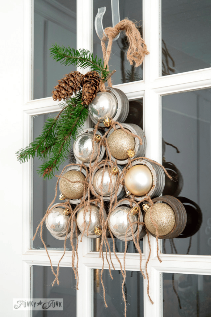 Mason jar lids in the shape of tree, each filled with gold and silver baubles and hung on a front door as a unique DIY wreath