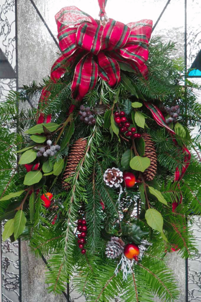 A selection of gathered festive branches held together at the top with a red ribbon