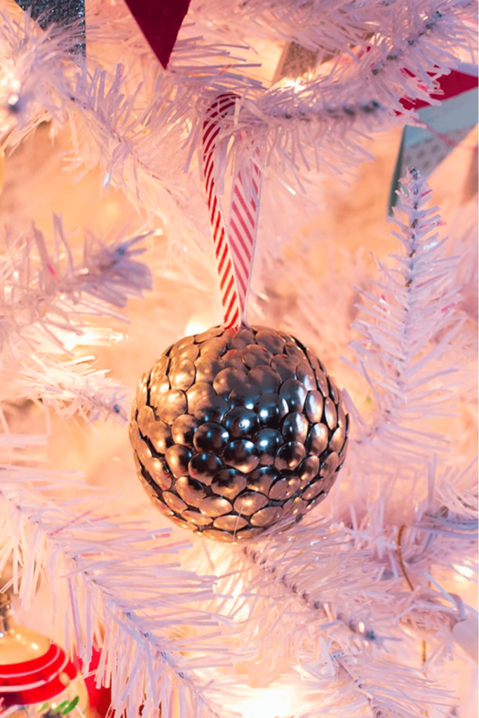 Ornament made with thumbtacks hanging on a white tree