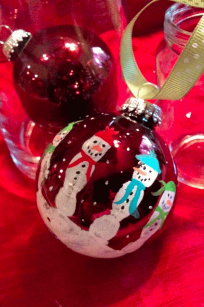 Shiny red bauble painted by hand with snowmen