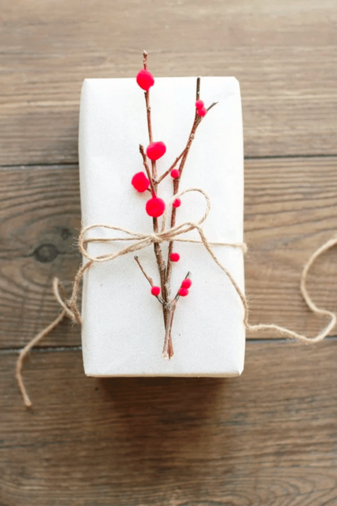 Twig with red pom pom berries on a white gift