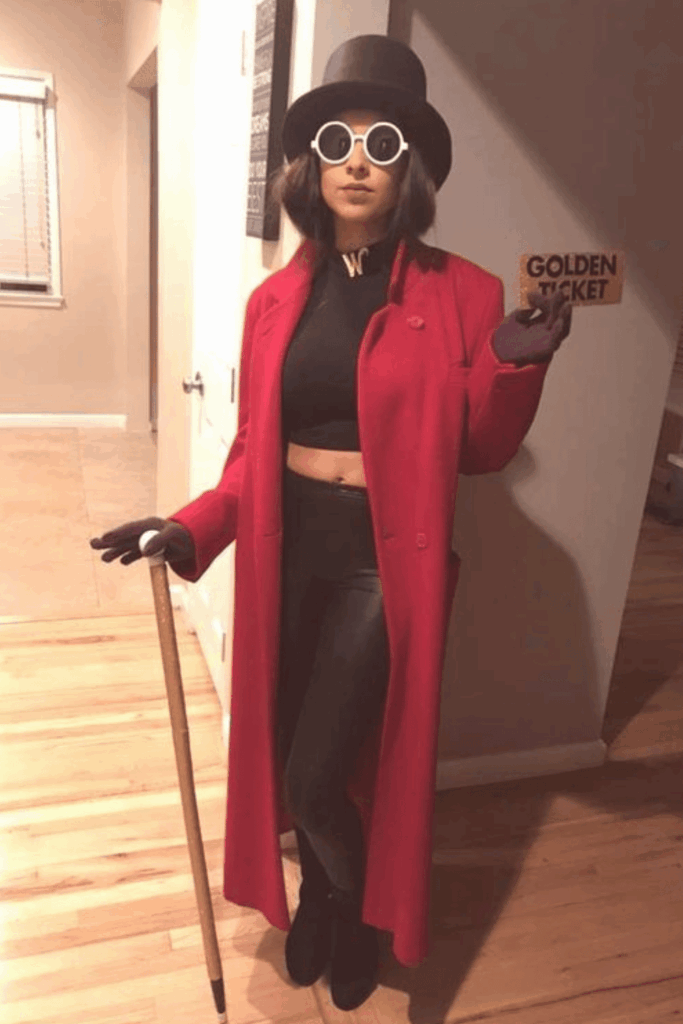 Woman dressed as a modern Willy Wonka with a red coat, black crop top, top hat, and golden ticket in hand.