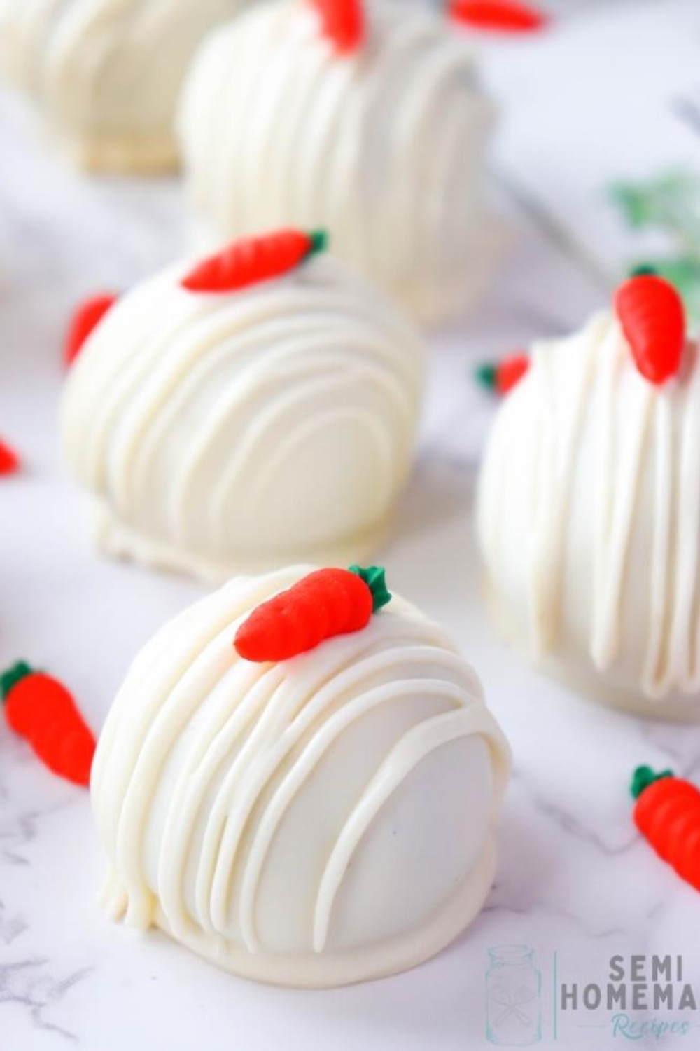 Bite-sized carrot cake truffles coated in white chocolate and topped with tiny edible fondant carrots.
