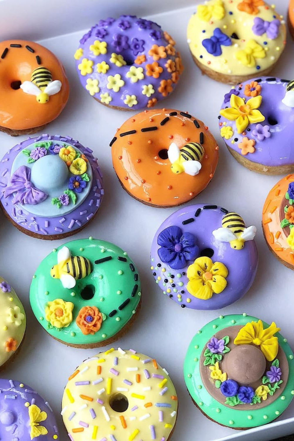 Colorful donuts decorated with icing flowers, bee-shaped candies, and bright spring designs.