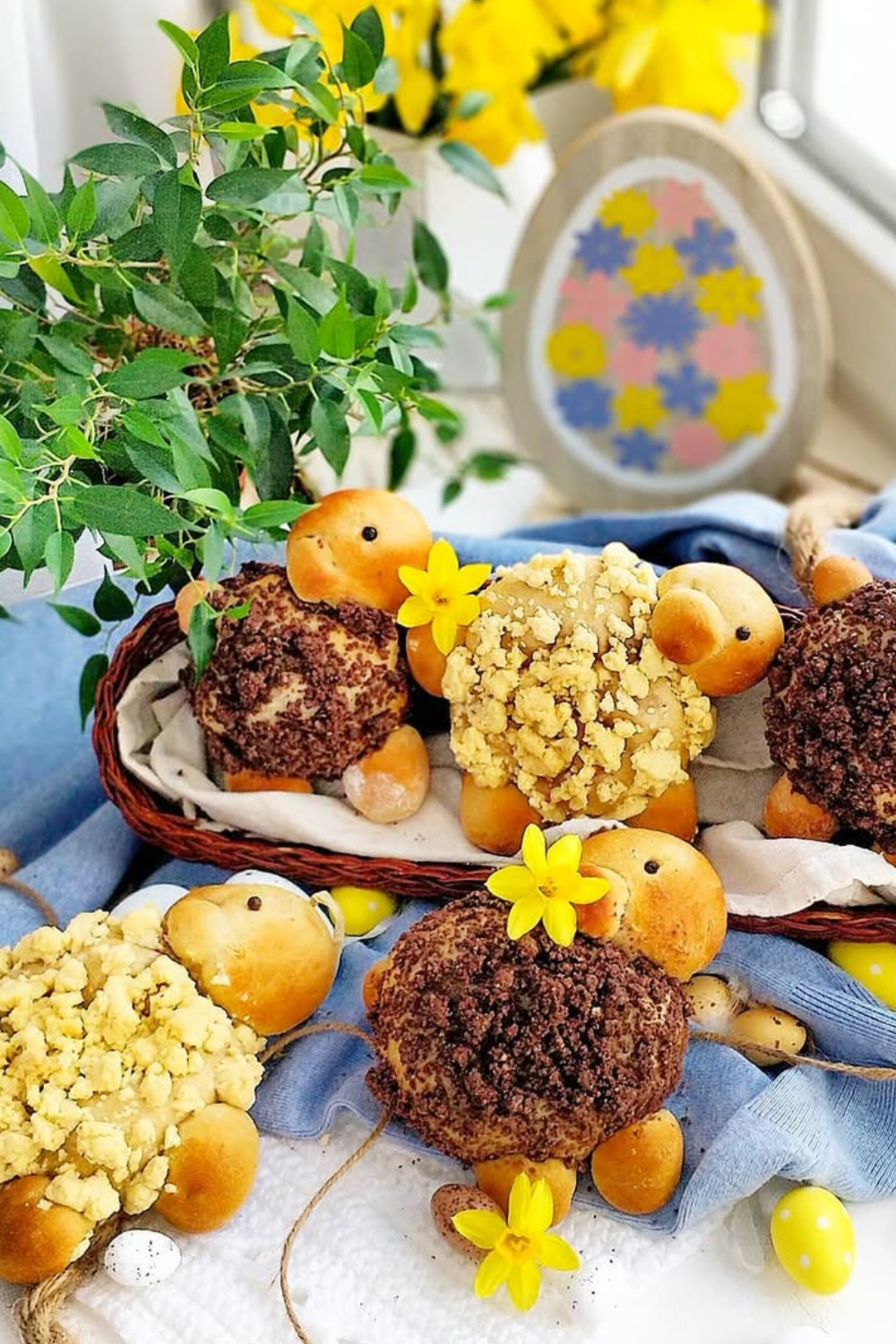 Fluffy lamb-shaped chocolate desserts with crumbly topping, arranged in a basket with yellow flowers.