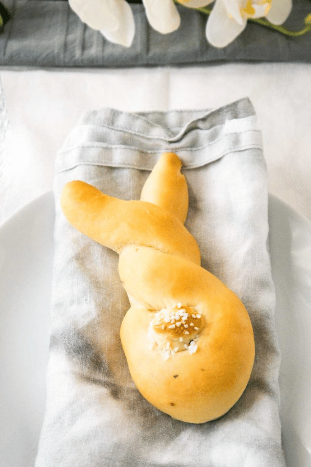 A single bread roll shaped like a bunny, placed on a folded napkin.