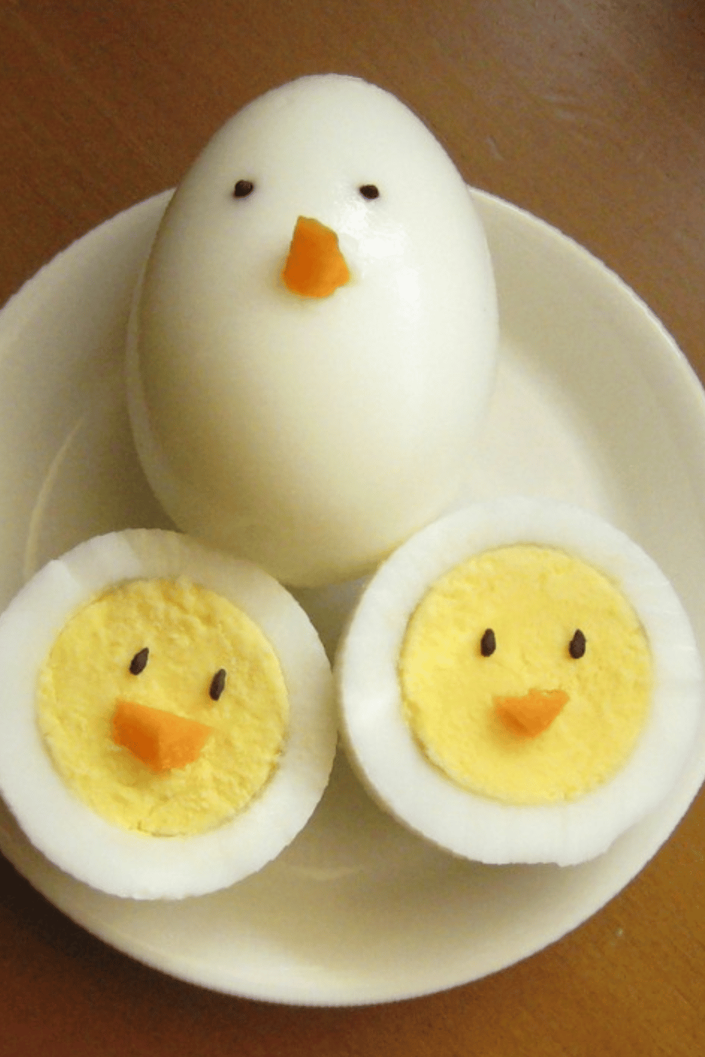 Boiled eggs decorated to resemble Easter chicks with small carrot noses and black eyes.