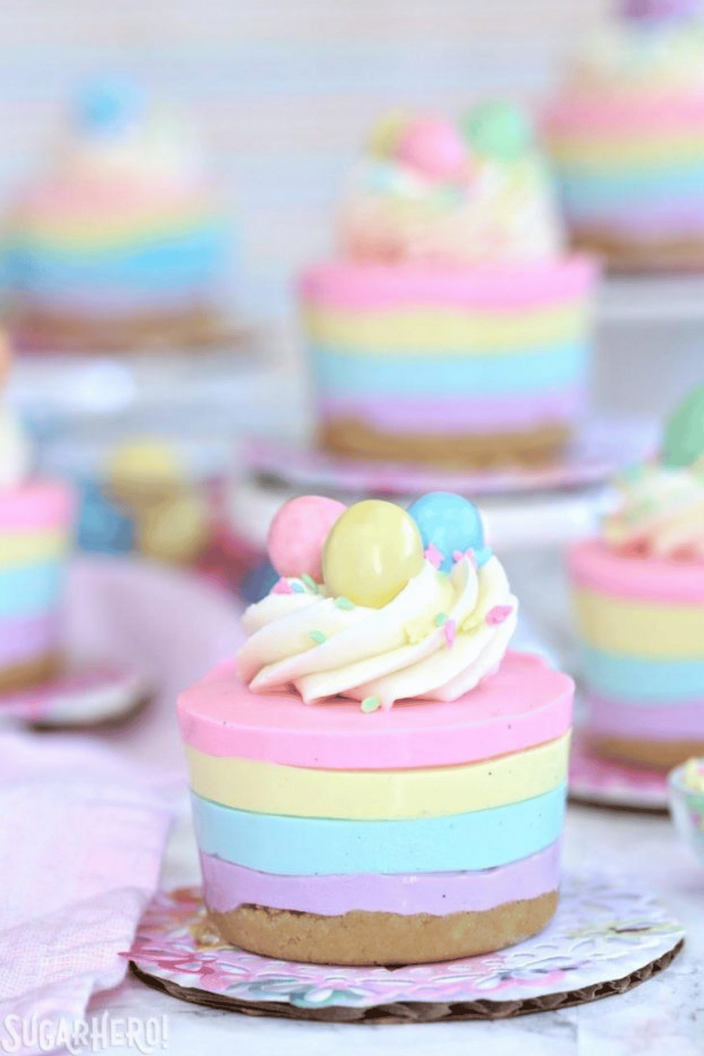 Pastel-colored layered mini cheesecakes topped with mini eggs and sprinkles.