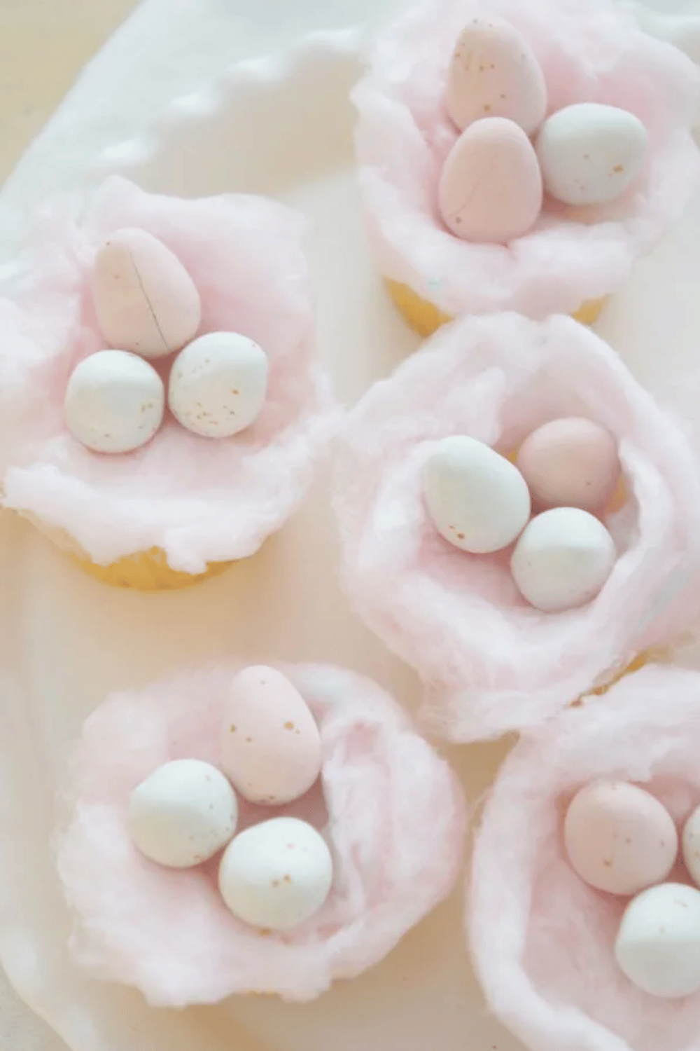 Cupcakes topped with cotton candy "nests" and pastel candy eggs.