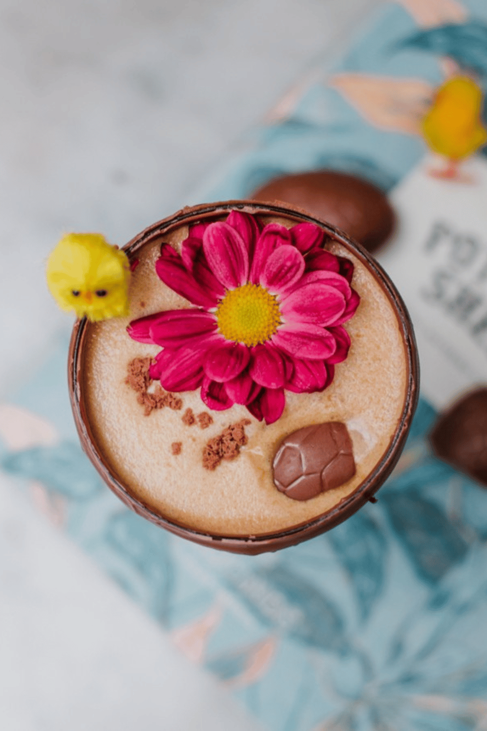 An espresso martini served in an edible chocolate egg, decorated with a flower garnish.