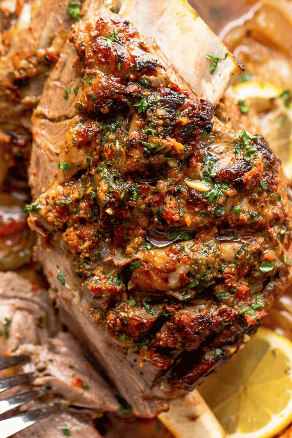 Herb-crusted roast lamb with a golden crust on a platter with lemon slices.
