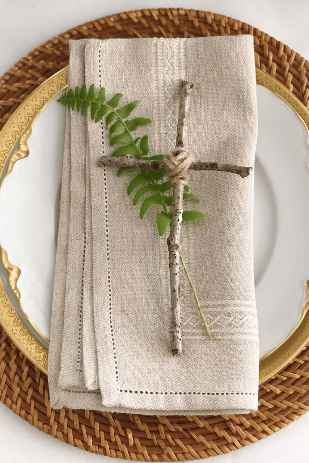 Minimalist Easter dinner table setting with a natural twig cross, linen napkins