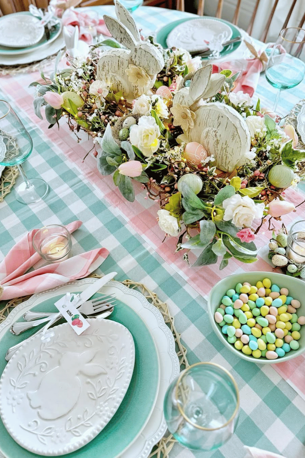 Gingham and pastel Easter hosting ideas with green-and-white linens, wooden bunnies, and painted Easter eggs.