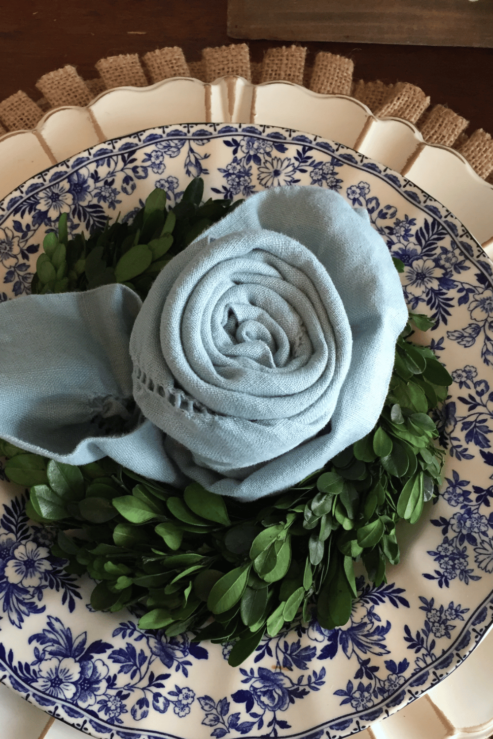 Floral napkin rose tablescape with a greenery wreath on classic blue china