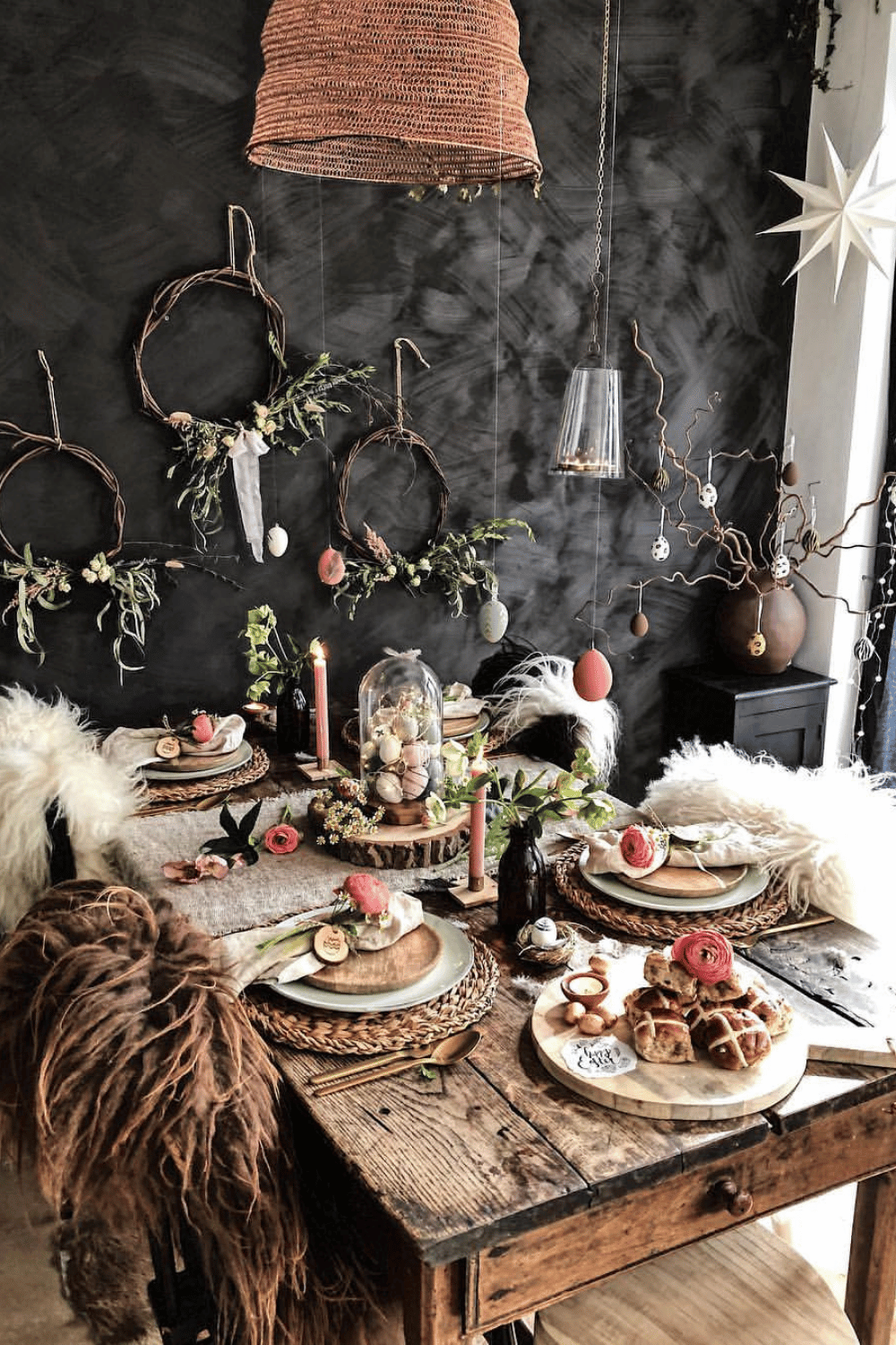 Dark and moody Easter Tablescape with dramatic lighting, fur throws, and rustic hanging egg wreaths.