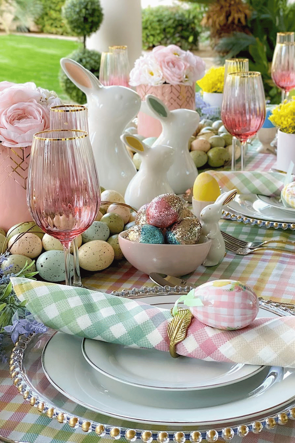 Gingham and glitter Easter dinner table setting with pastel prints, gold-rimmed glasses, and soft pink florals.