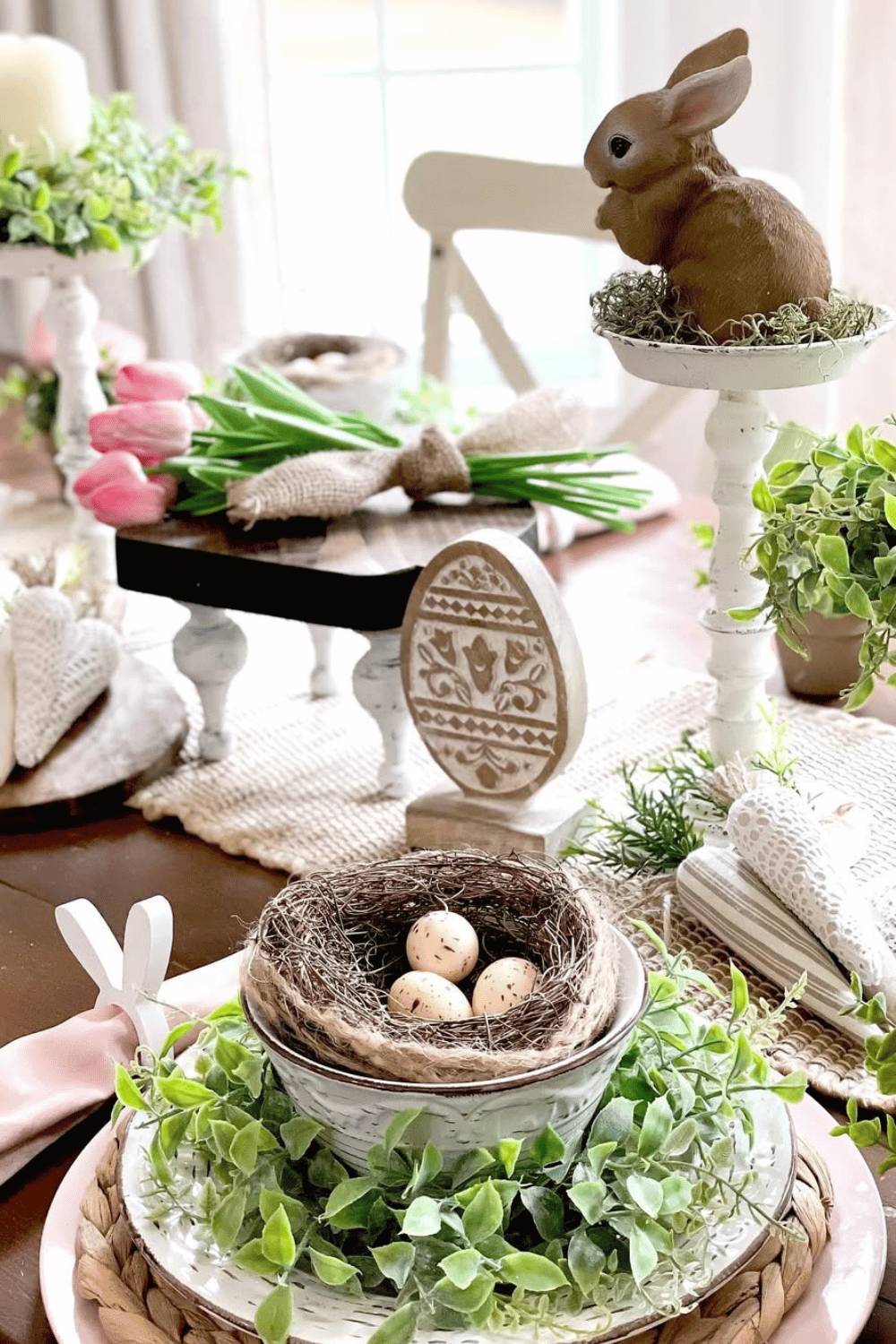 Farmhouse Easter table setting with bird nests, greenery, and wooden accents.
