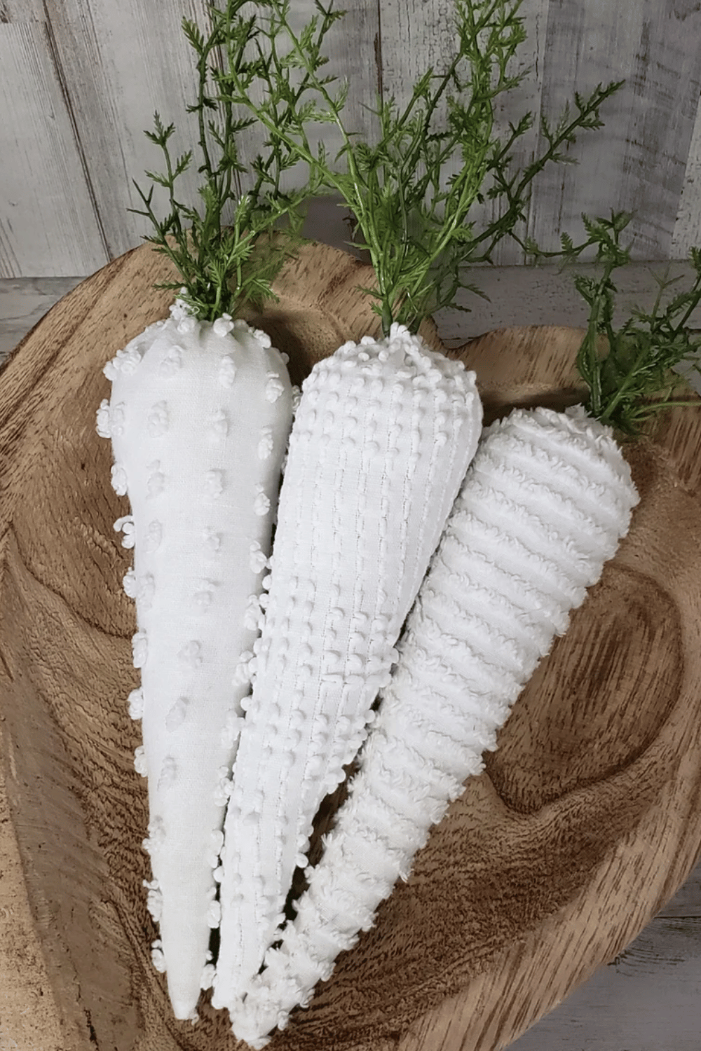White fabric carrots styled in a wooden bowl for a minimalist touch.