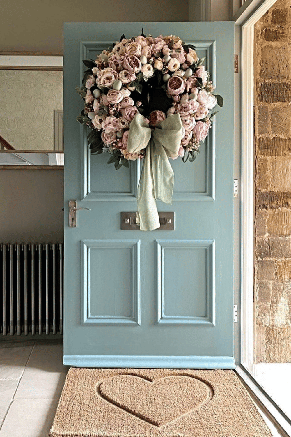 Floral Easter wreath with soft pastels and a green ribbon on a front door.