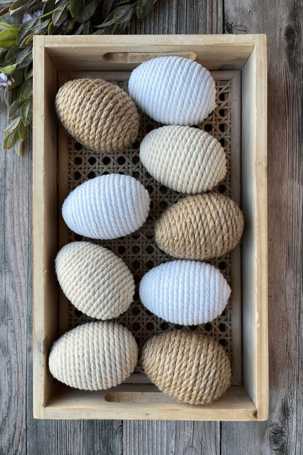 Rustic twine-wrapped eggs displayed in a wooden crate.