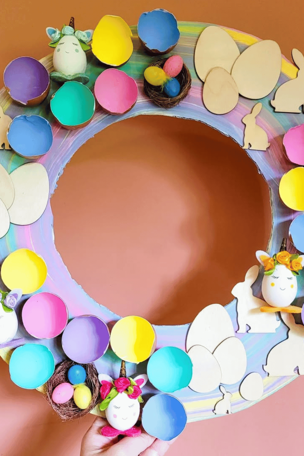 A cheerful Easter wreath showcases vibrant rainbow eggs alongside charming wooden bunny designs.