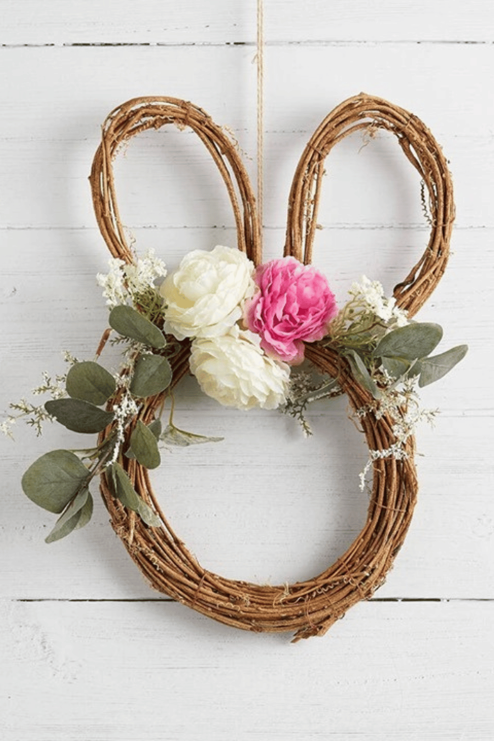 This Easter wreath combines a grapevine base shaped like a bunny and decorative floral elements.