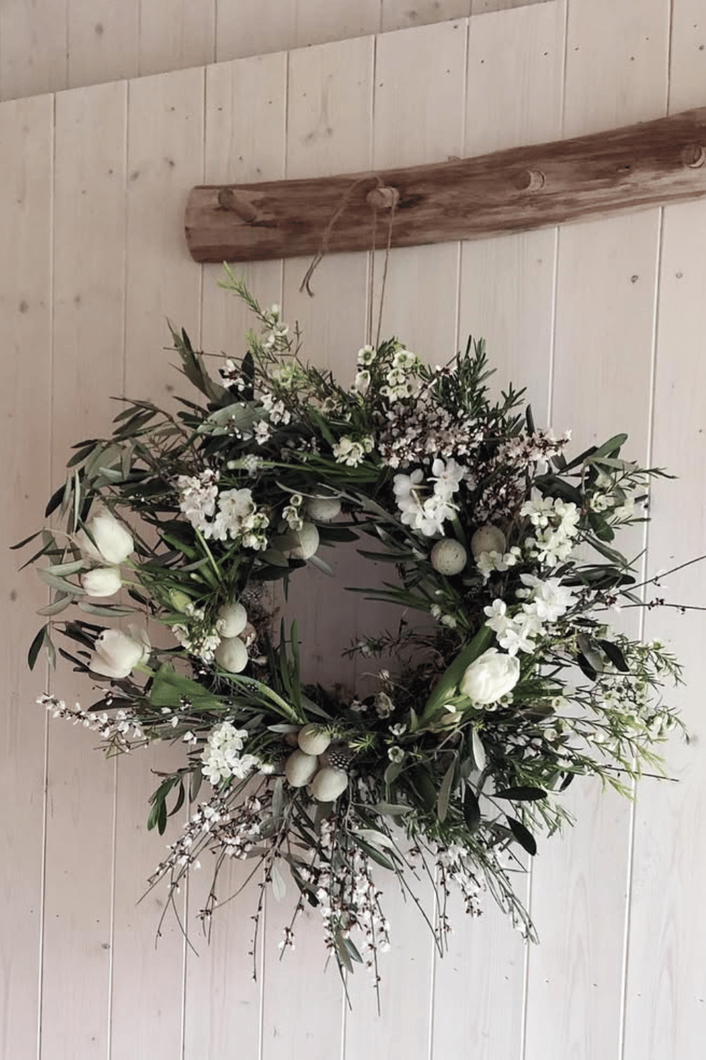 The Easter wreath combines white tulips and greenery in muted neutral colors.