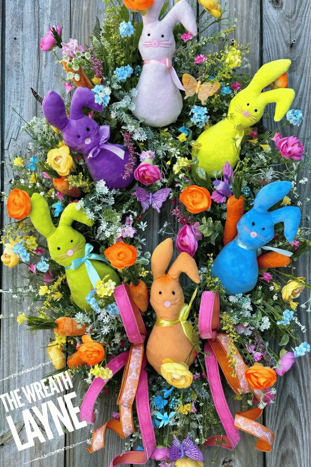 An Easter wreath featuring bright colors and plush bunny decorations alongside flowers.