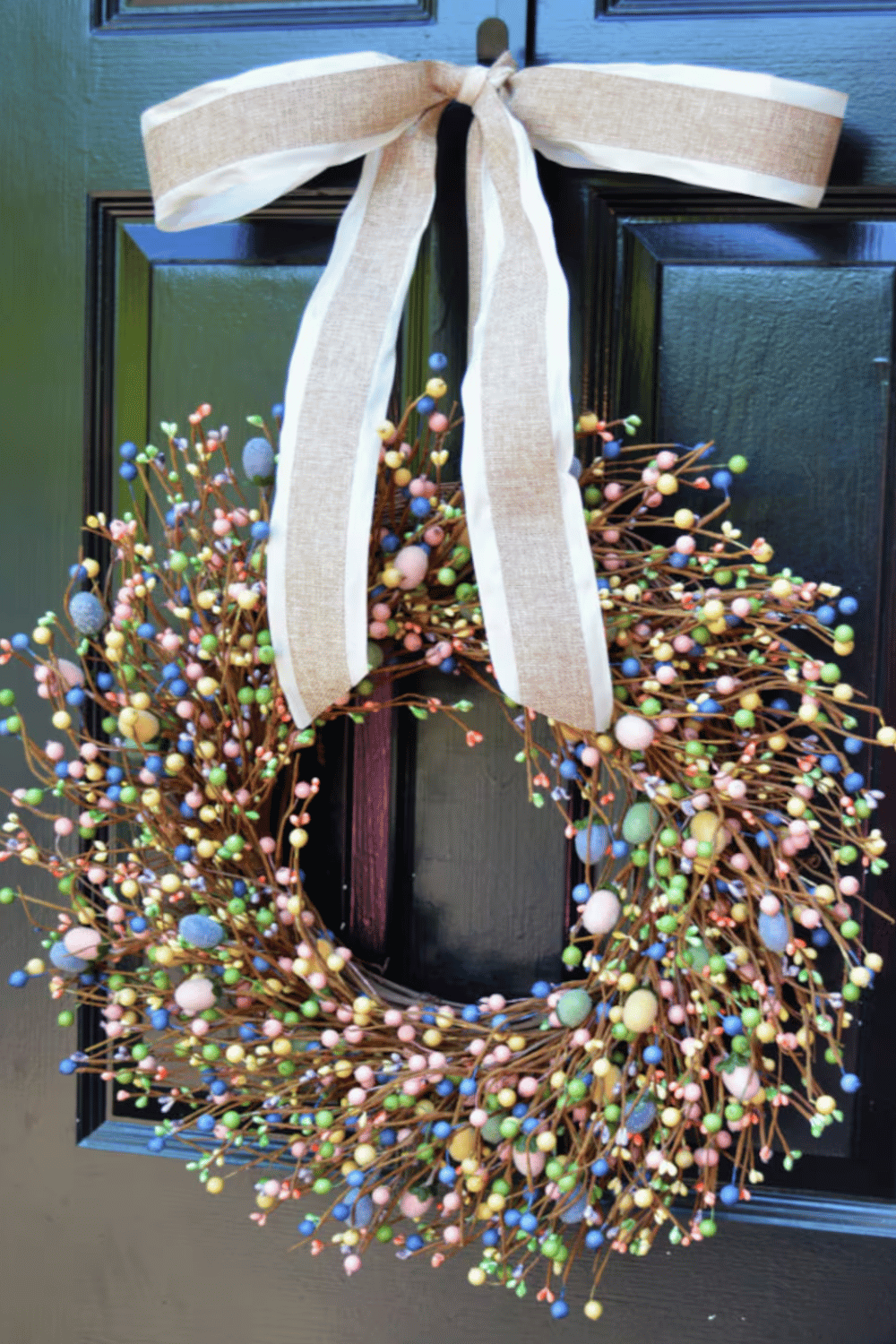 Easter wreath made from burlap featuring berries and eggs with an accompanying rustic bow.
