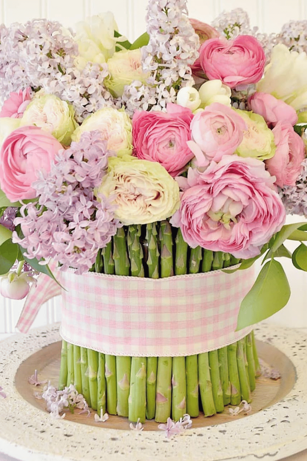 Pastel spring blooms wrapped with asparagus stalks and gingham ribbon for a unique centerpiece