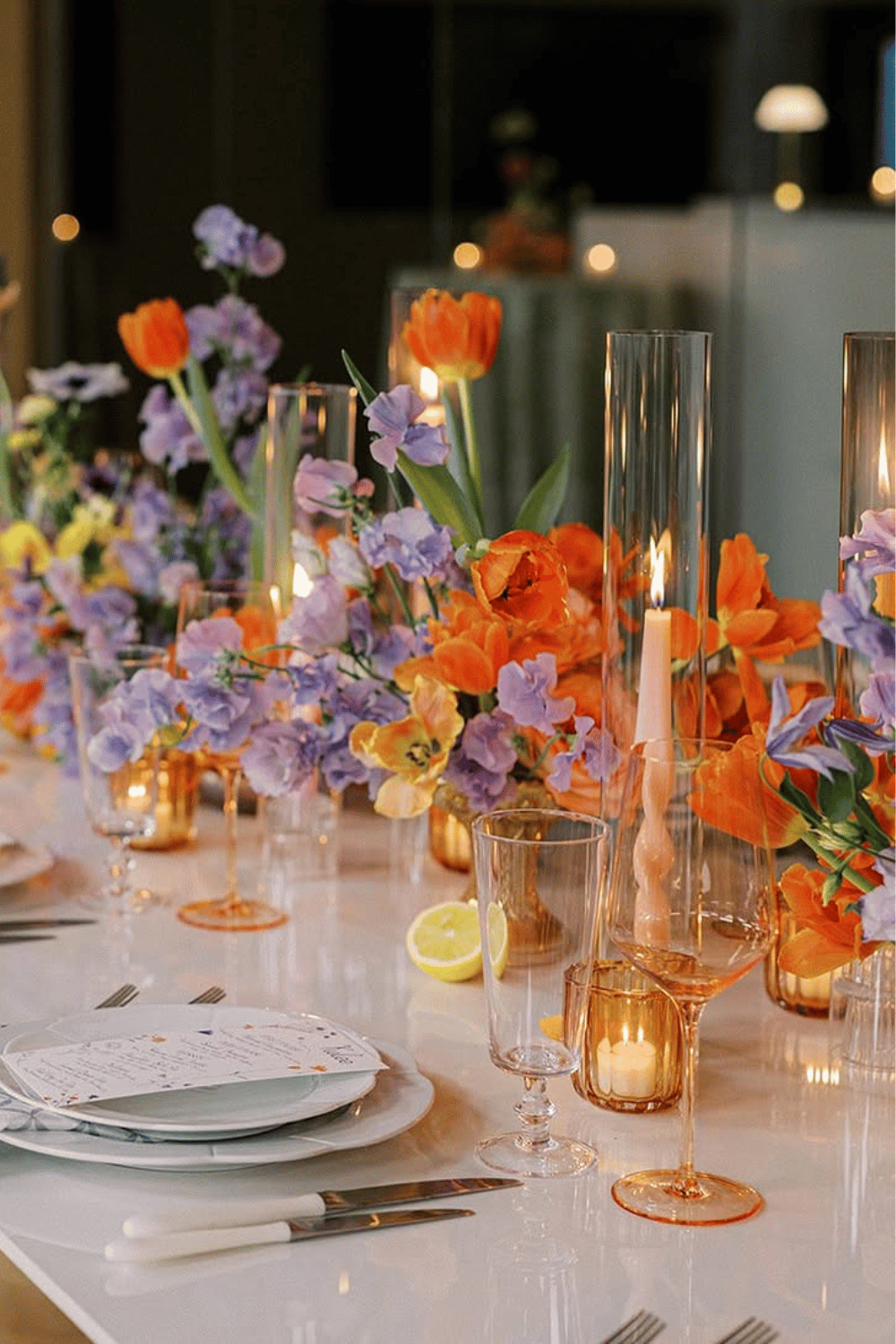 Bold orange and purple flowers with candles styled for a colorful spring tablescape
