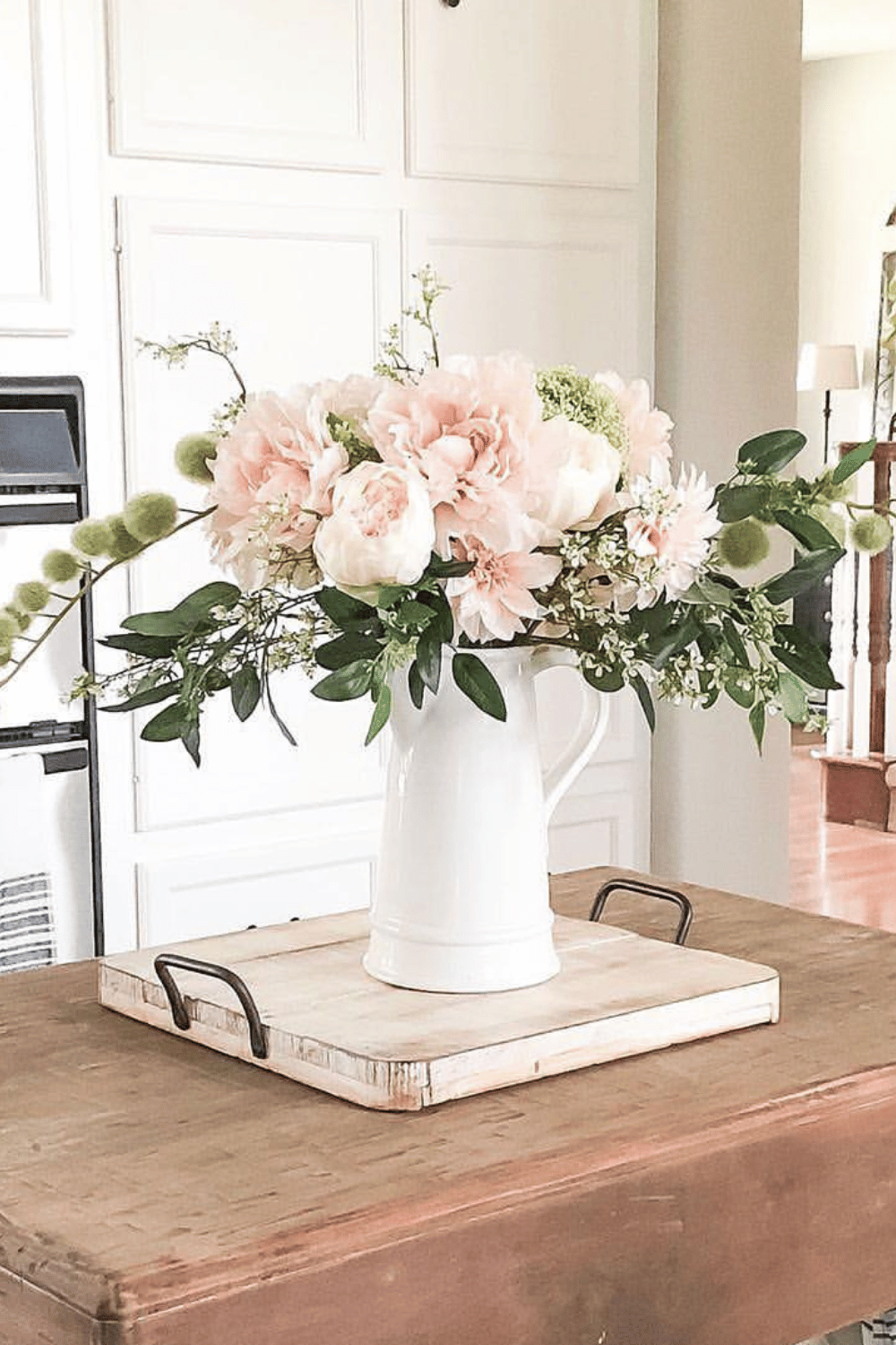 White pitcher filled with blush peonies and greenery as a simple spring centerpiece