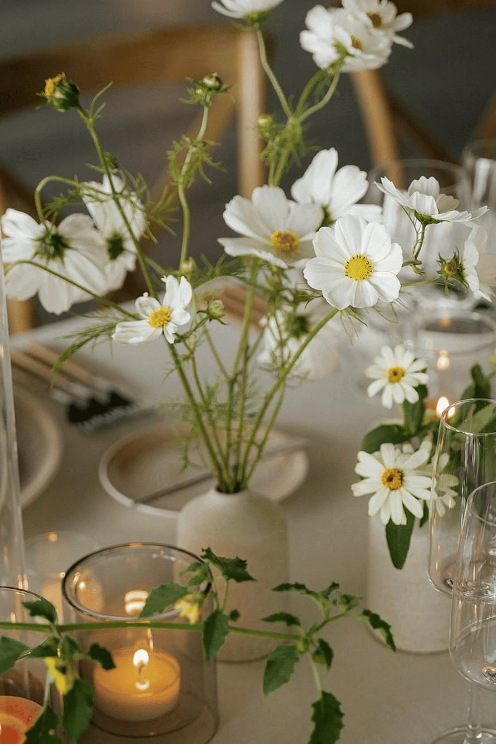 Minimal white daisies in small vases with candles for an elegant spring dining table setting