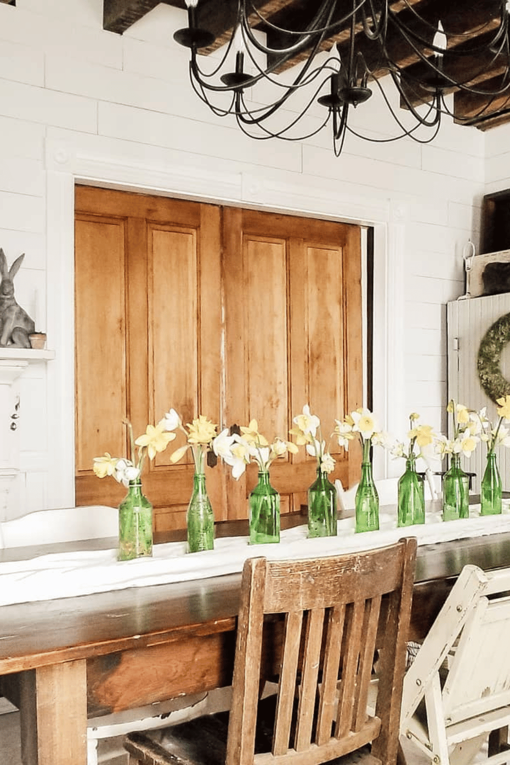 Row of vintage green bottles holding fresh daffodils as spring dining table decor