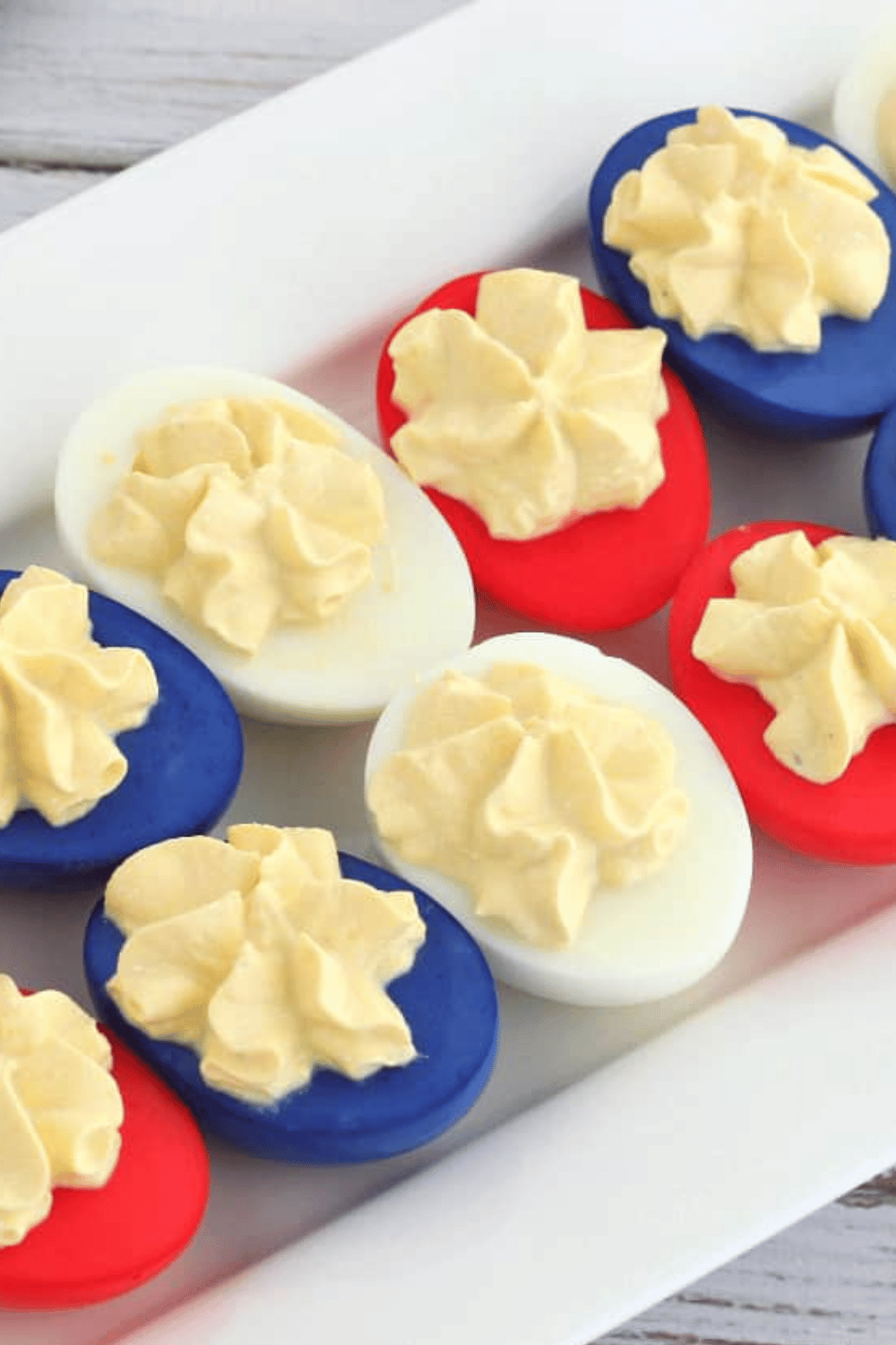 Red, white, and blue deviled eggs arranged on a white serving tray