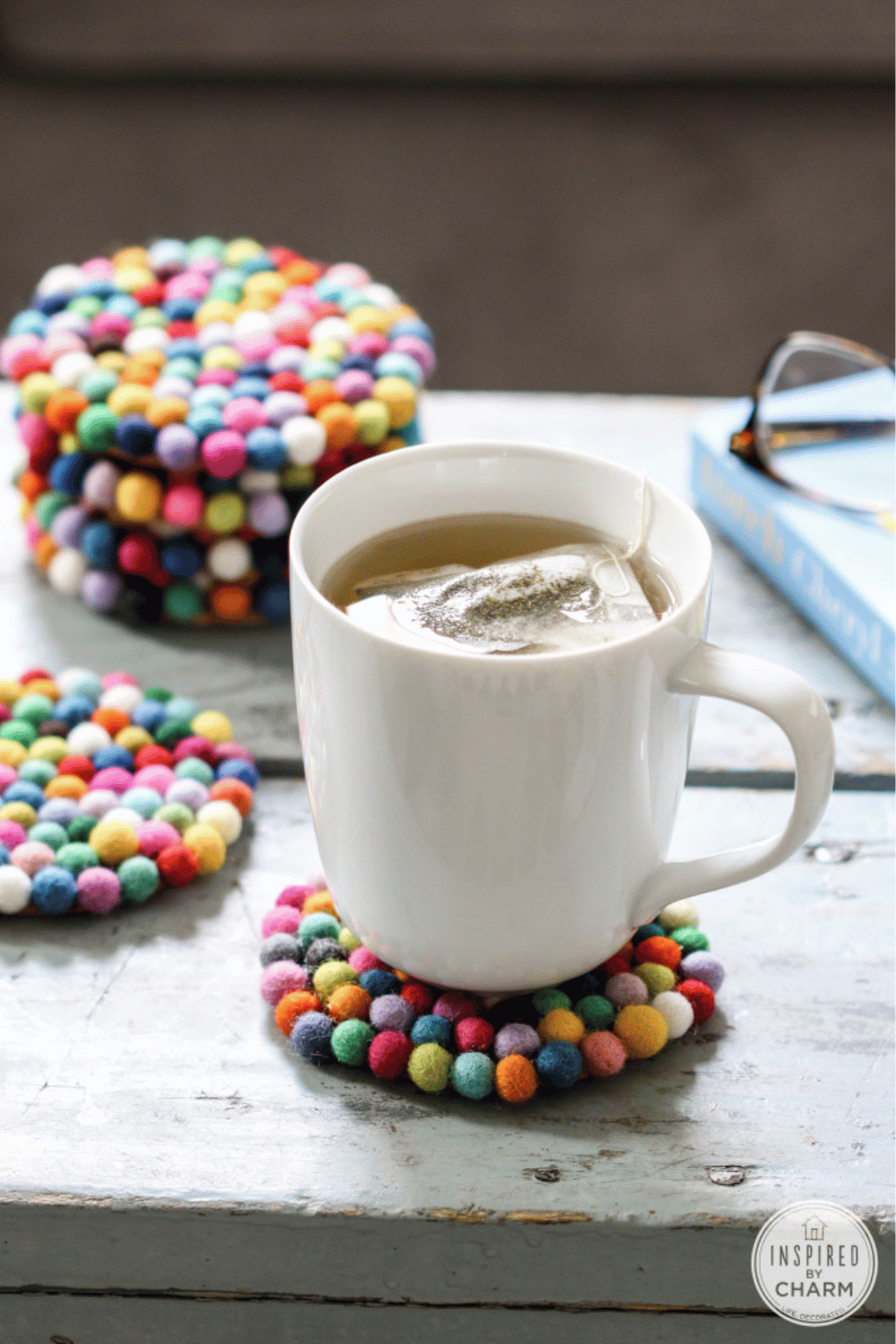 Bright wool felt ball coasters arranged on a wooden surface