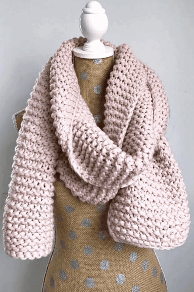 Chunky hand-knitted blush scarf on a mannequin