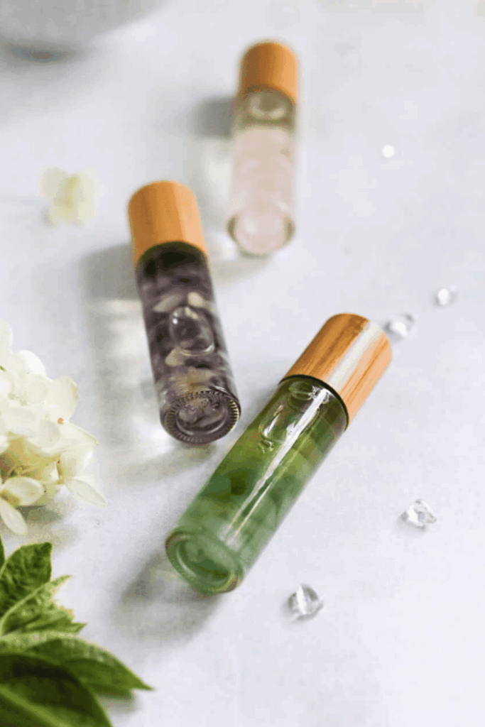 Three glass roll-on bottles of essential oil blends with wooden caps
