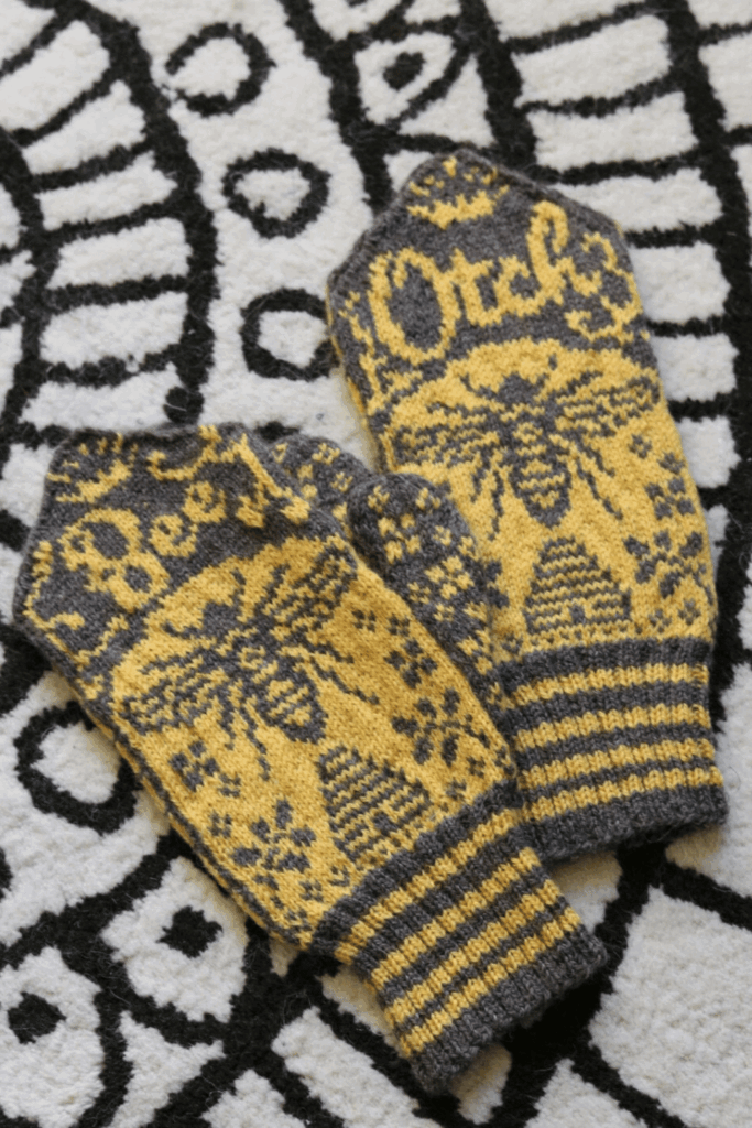 Yellow and gray knitted mittens with bees and floral patterns