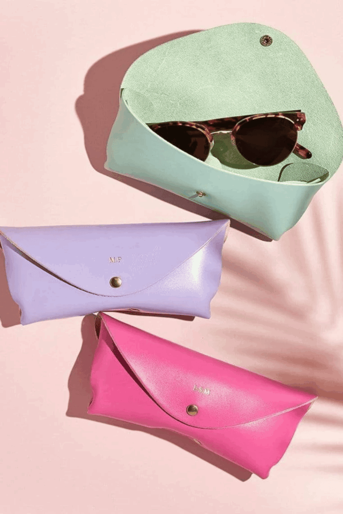 Three colorful leather glasses cases, one open with sunglasses inside