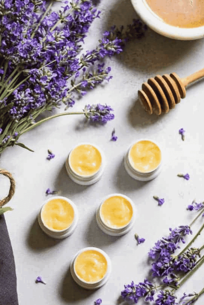 Small lip balm containers with lavender flowers and a honey dipper