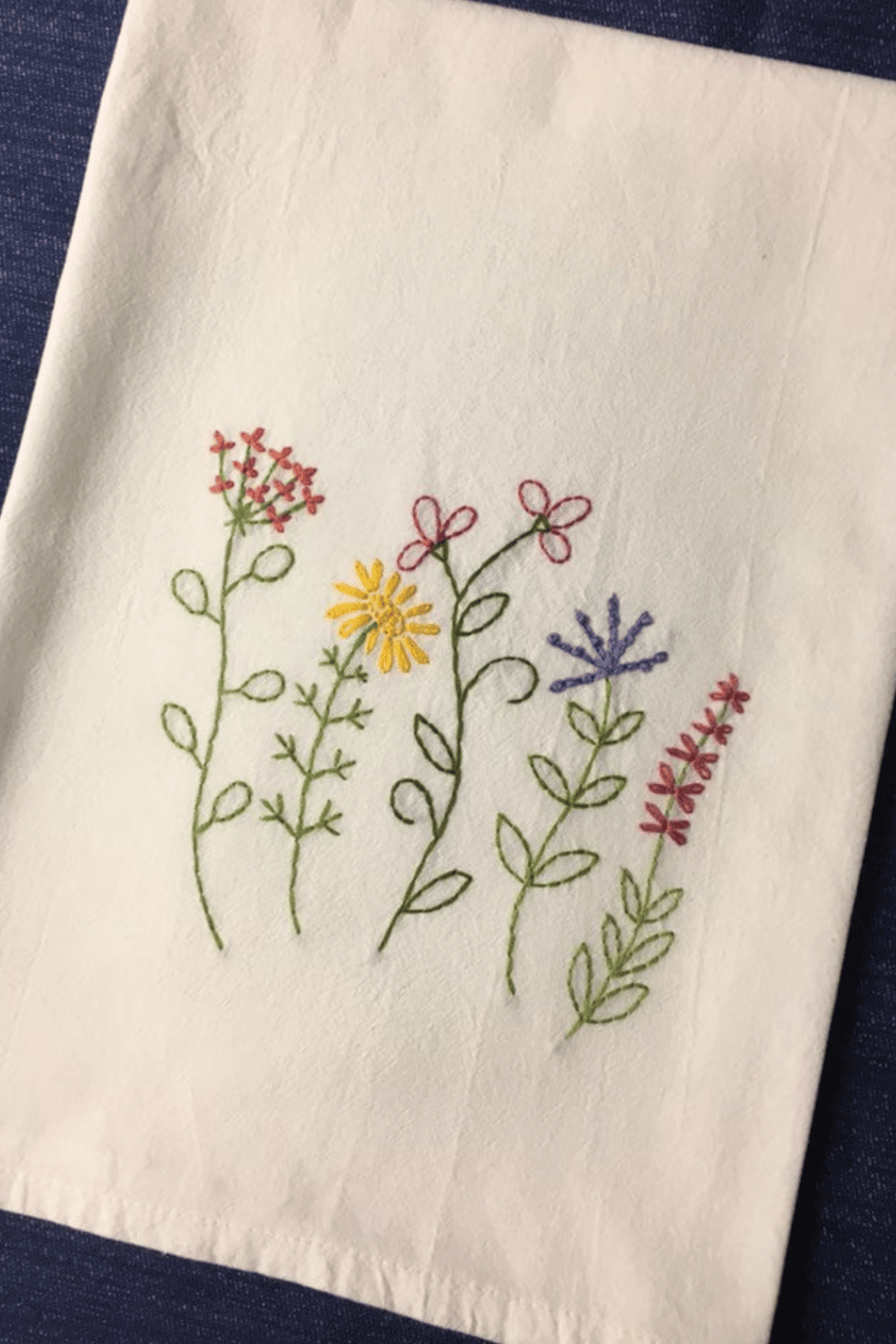 Hand-embroidered cotton tea towel with colorful wildflowers