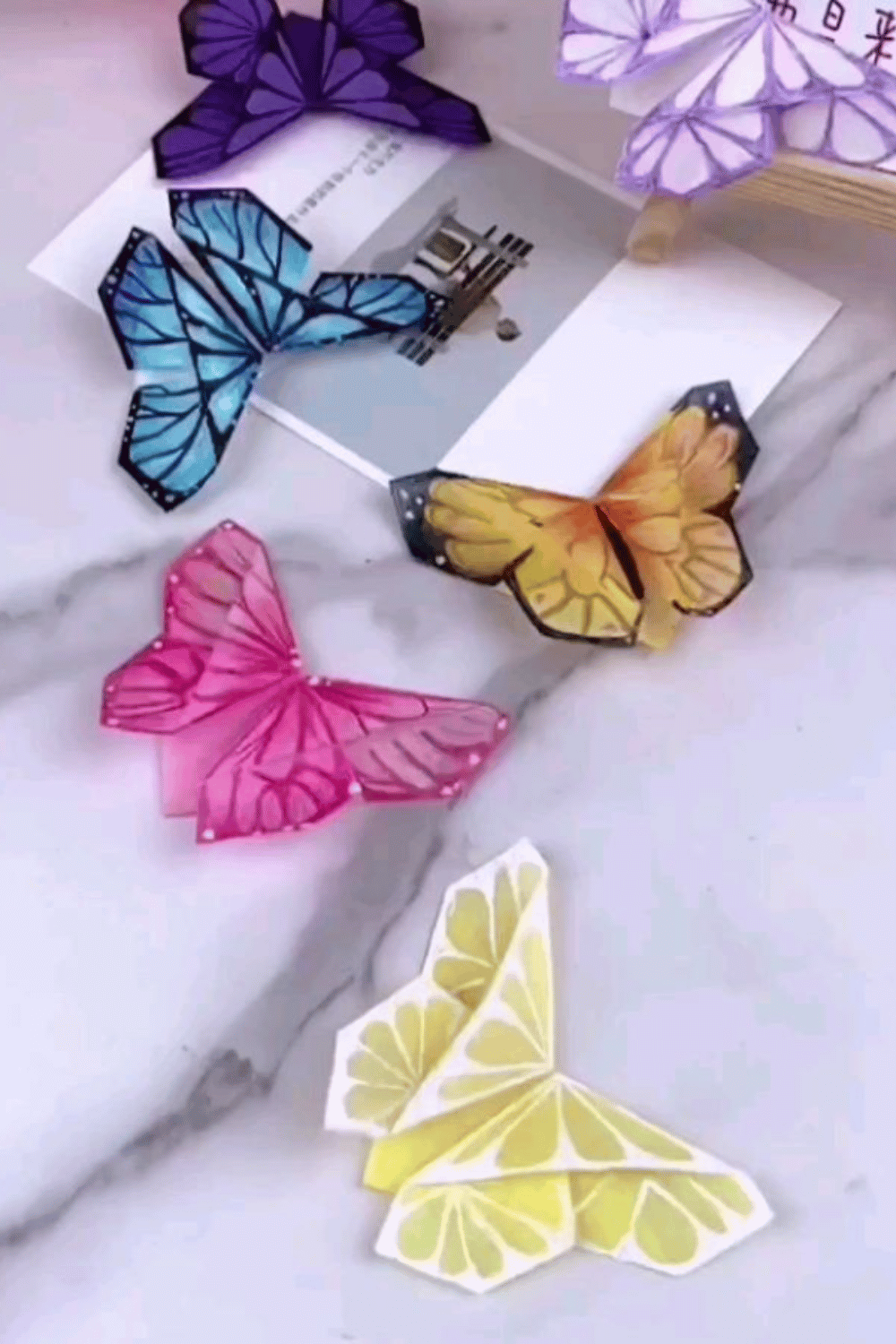 Colorful pop-up butterfly bookmarks displayed on a marble surface