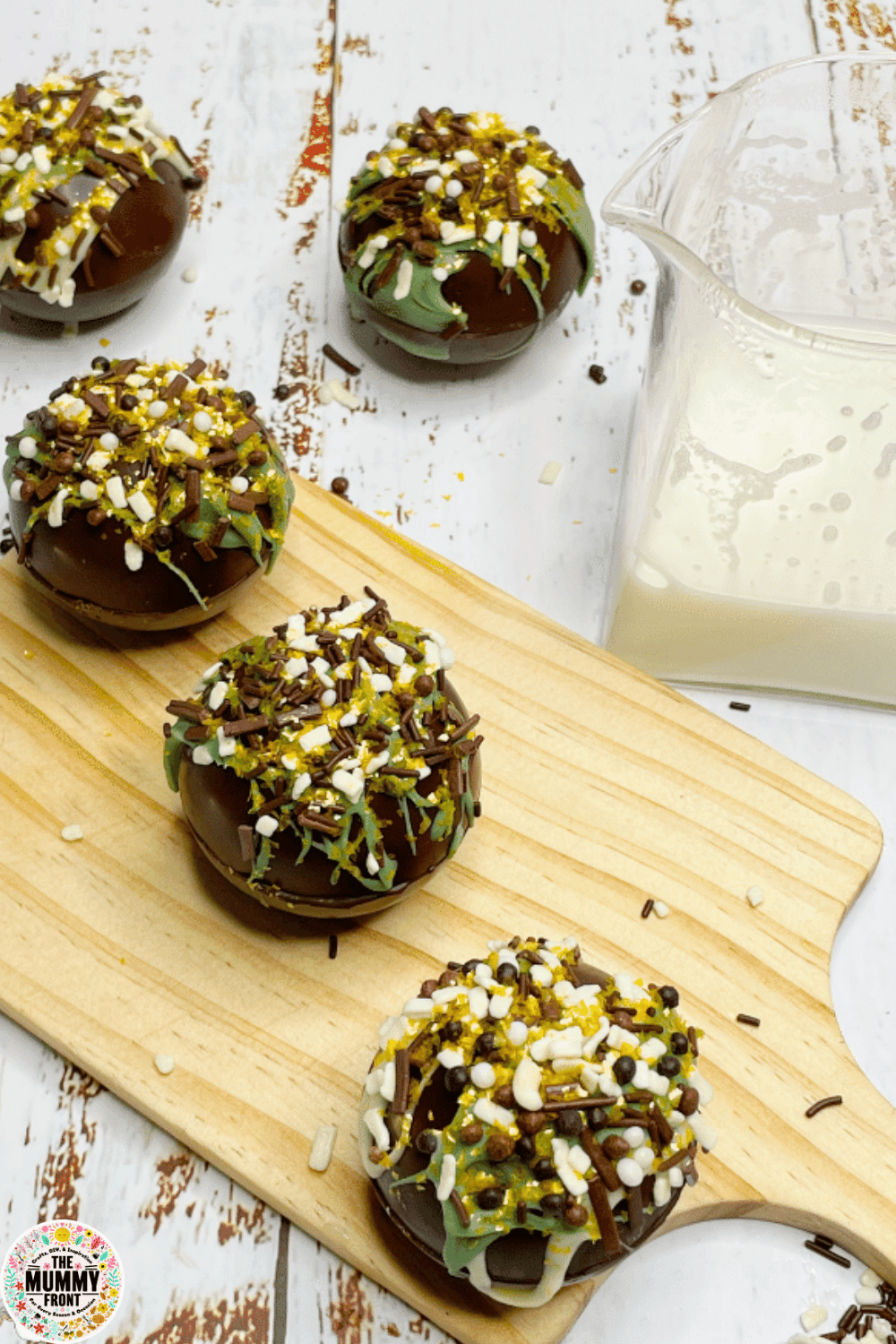 Hot chocolate bombs decorated with sprinkles on a wooden board