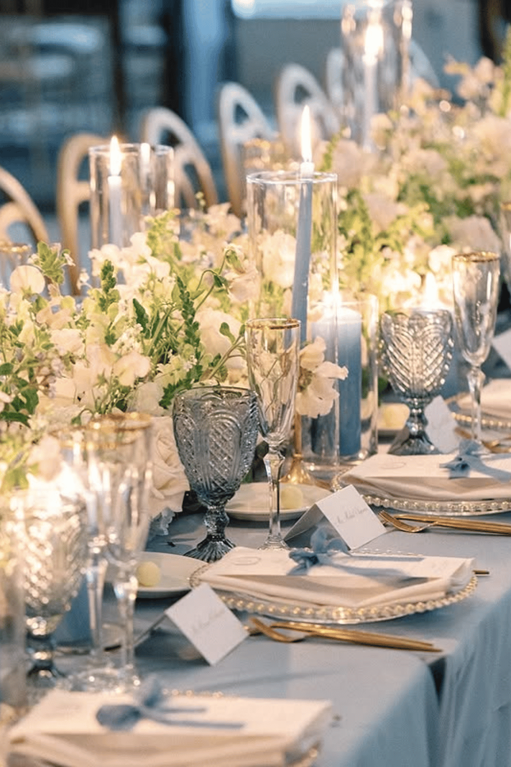 Romantic dusty blue tablescape with layered candles and soft white blooms