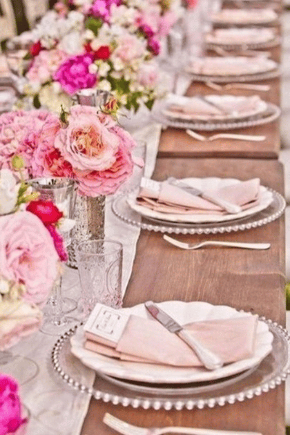 Soft pink floral wedding table with beaded charger plates and blush napkins
