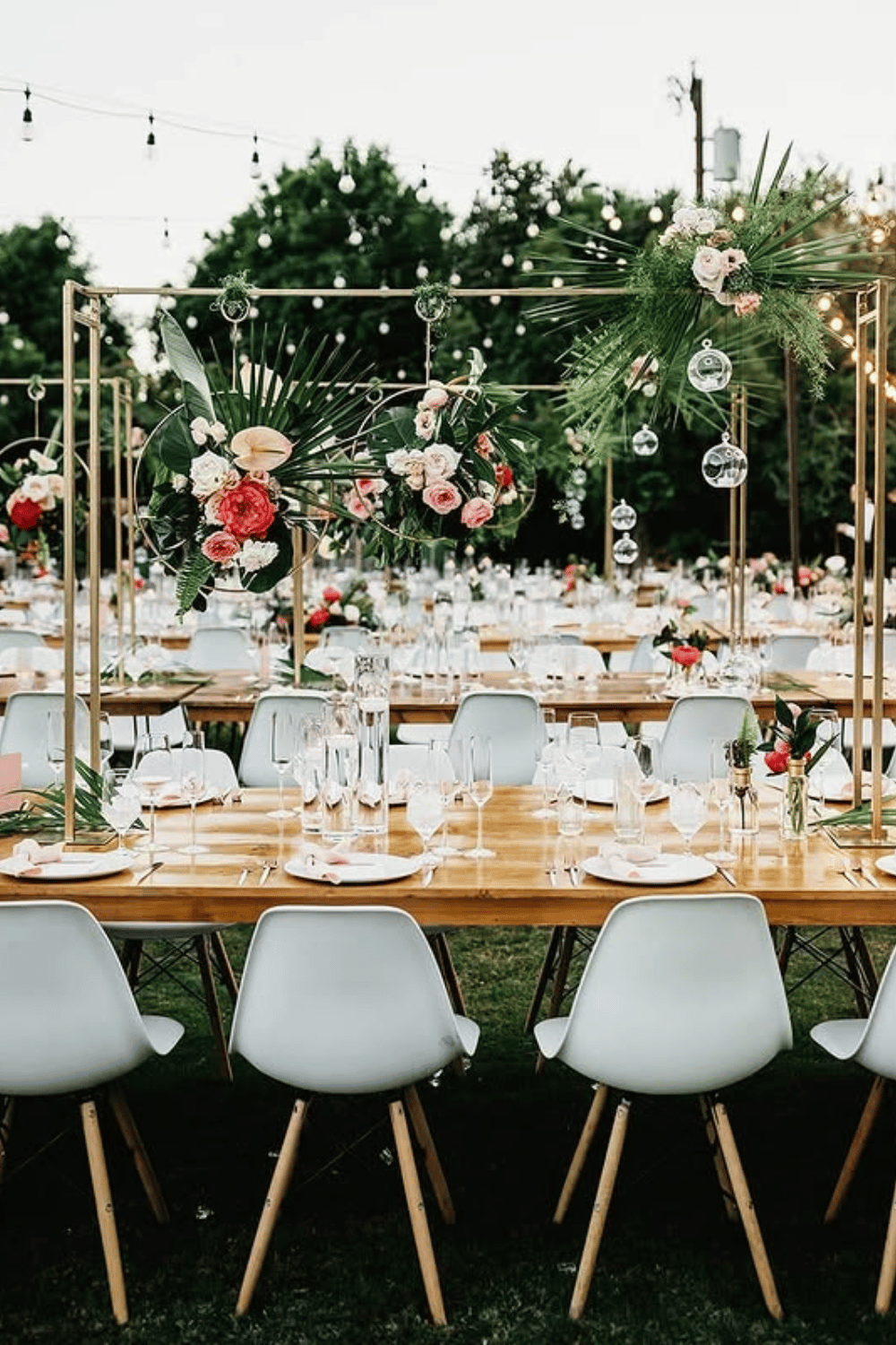 Outdoor wedding with suspended floral arrangements over wooden tables