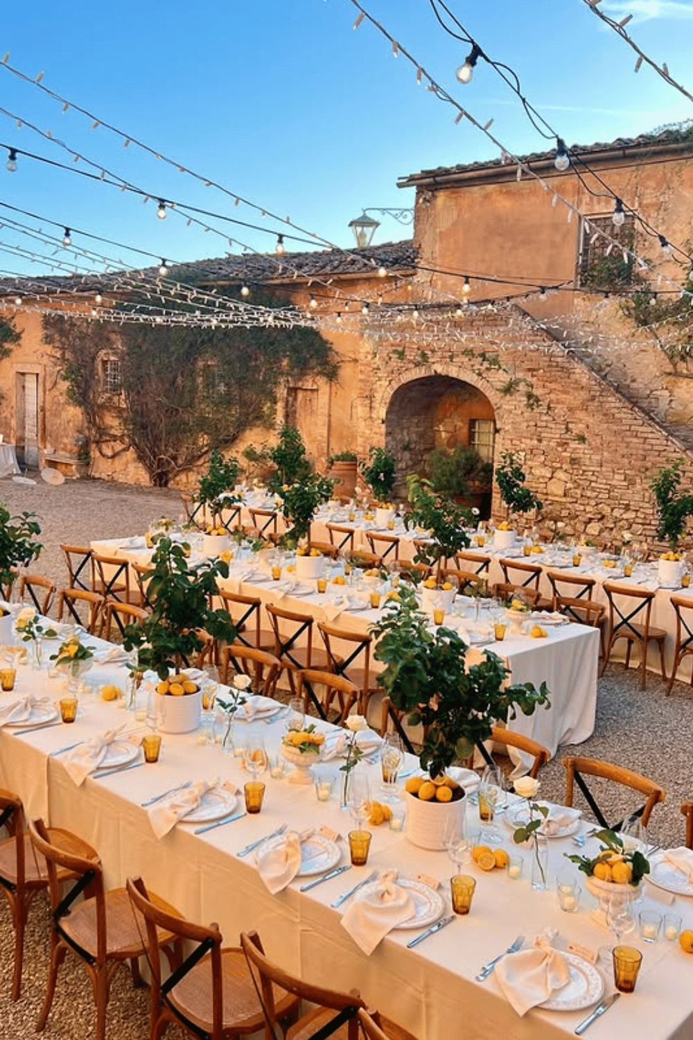 Lemon-inspired wedding table setup in a rustic courtyard with citrus centerpieces. Wedding Tablescapes
