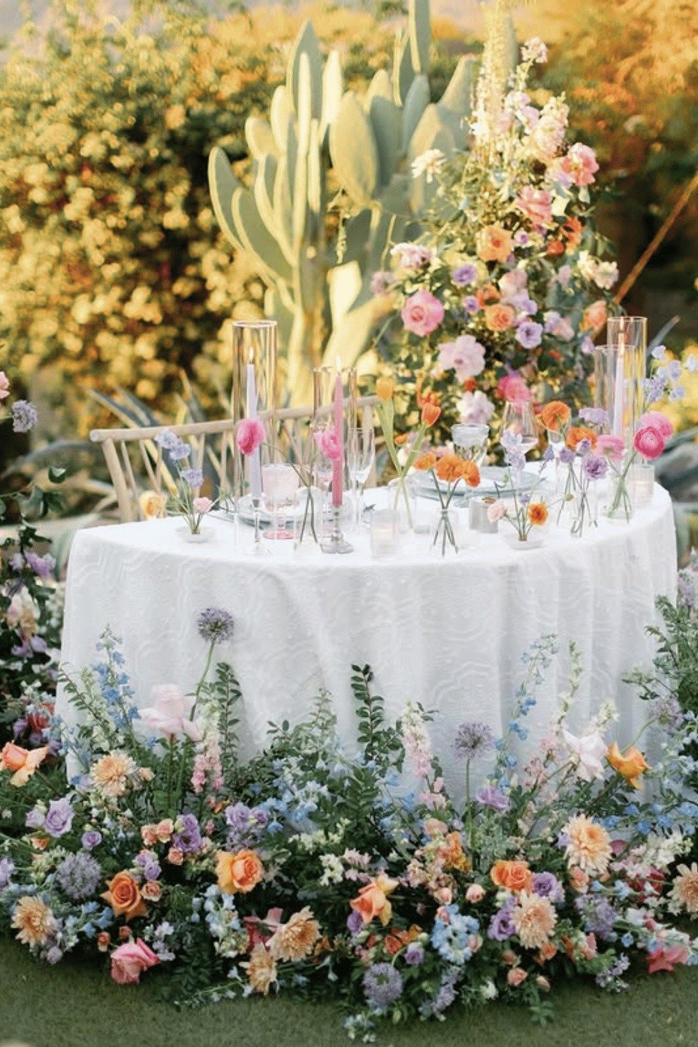 Sweetheart table surrounded by vibrant garden florals and romantic lighting. Wedding Table Setting Ideas