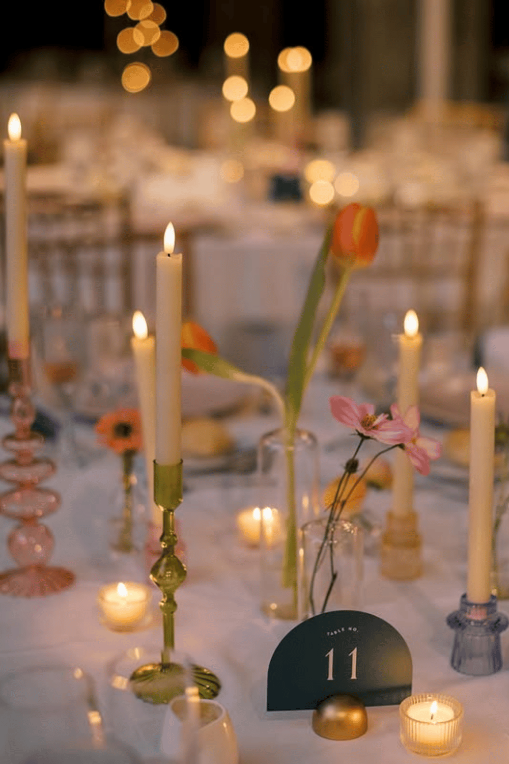 Artistic candlelit table with mismatched candle holders and minimal floral details
